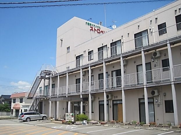 目の前に広い駐車場があり、外階段のある三階建ての建物