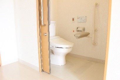 引き戸式のドアの向こうに温水洗浄機能付きトイレが設置されている。部屋からは段差がなく、車椅子をご利用の方も安全に移動することができる。