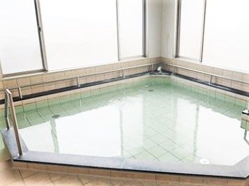 浴室の角にある三角形の浴槽。手すりが付き、壁はガラスとなっている。