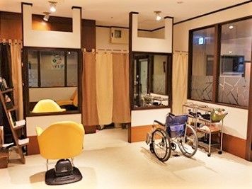 大きな鏡が二つ設置され、前には美容室用の回転チェアと車いすが置かれている。