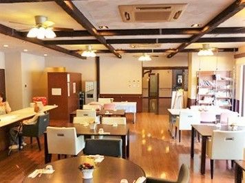 フローリングの床に白い壁、天井にはおしゃれなライトが設置され、４人掛けのテーブルが複数ある。
