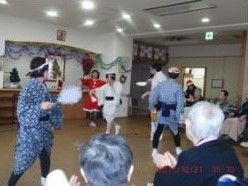 クリスマス会でひょっとこ踊りを披露するボランティアグループと、それを見学する入居者。