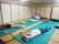 畳の部屋に緑のマットを敷き、座布団などを使用しながらストレッチをしている入居者たち。