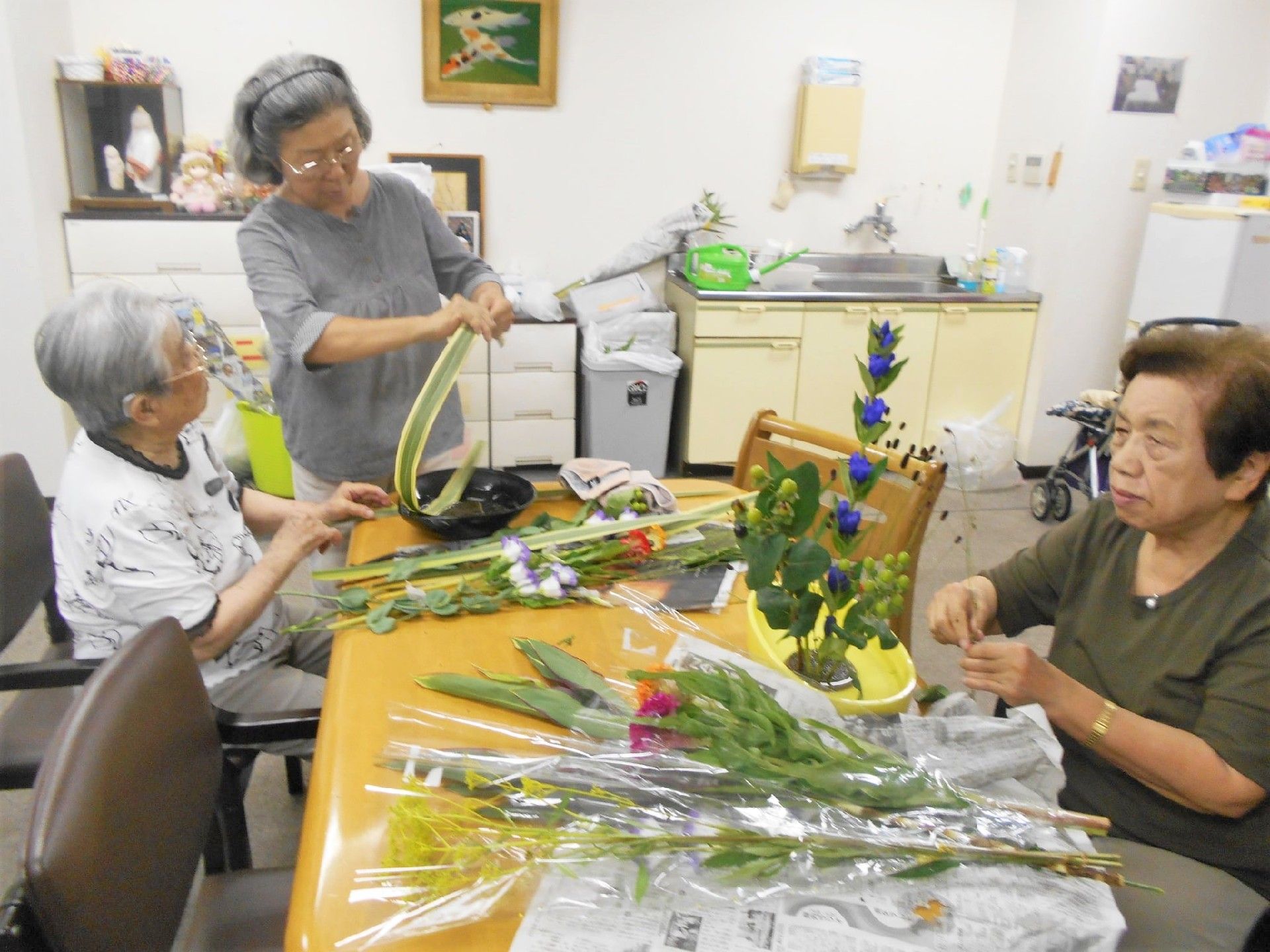 生け花を真剣な表情で行っている女性入居者と、指導する講師。