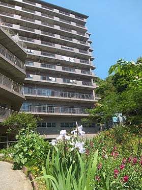 大きな建物はグレー系で花や木が周りに植えられている。