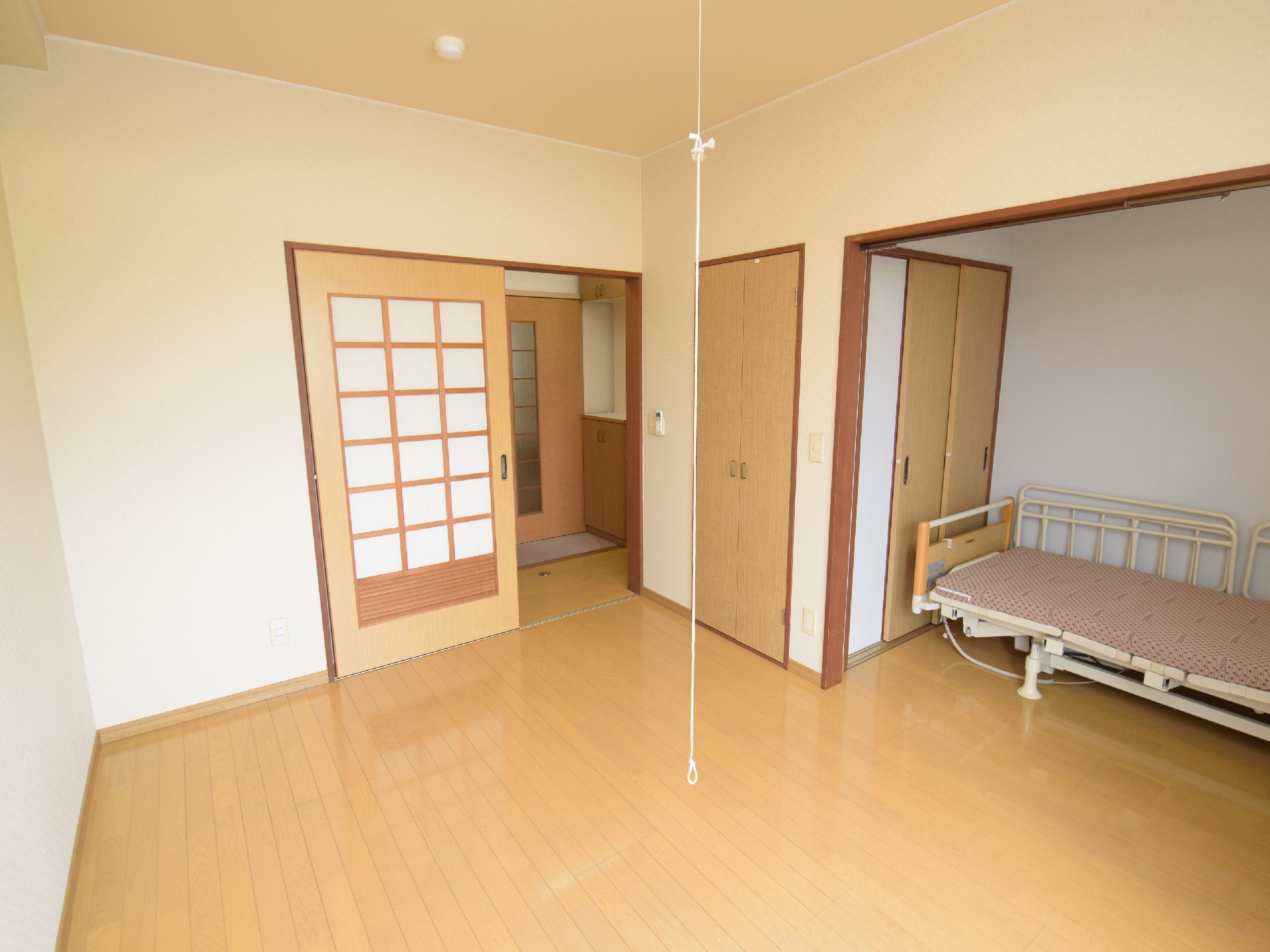 クローゼットと布団の敷いていないベッドがあるフローリングの部屋
