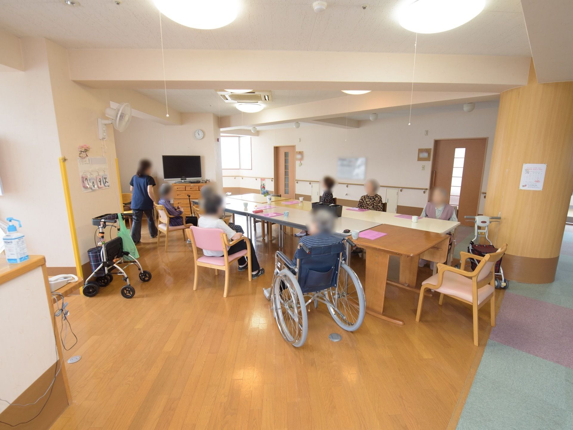広い部屋に並んだテーブルに向かい座る入居者たちとスタッフ