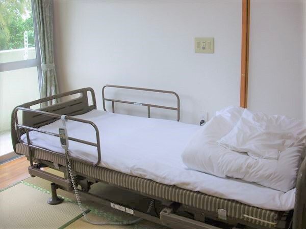 ベッドには寝具がセットされ、畳敷きの部屋には大きな窓があり、カーテンが付いている。