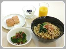 うどんと副菜、デザートとジュースが付いた献立
