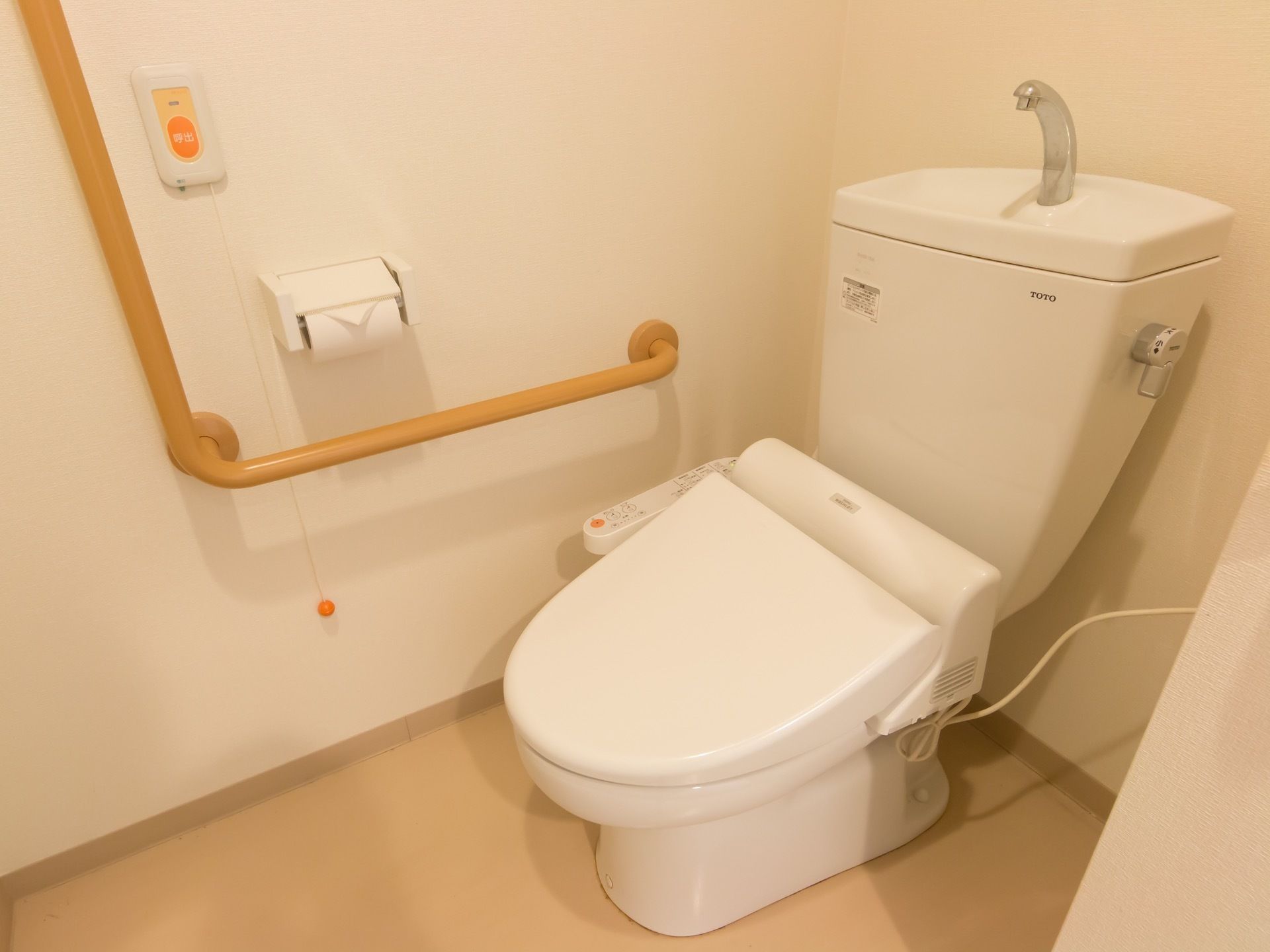 温水洗浄便座付きのトイレである。トイレの壁には手すりが設置されている。トイレ内には緊急連絡用のボタンが用意されている。