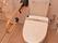 トイレの壁には、淡いピンク色のタイルが貼り付けてあり、頑丈な手すりも設置されている。その横には、ストライプ模様のカーテンがある。