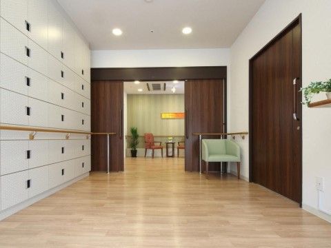 エントランスの棚やコーナーには、手すりが設置してある。扉付きの白い棚は、開け閉めする部分に穴が空いているデザインである。