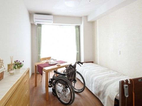 居室は可動式のベッドが設置してあり、コードの付いたリモコンをベッドの縁にかけている。車椅子でテーブルに付いて、お茶が飲める。