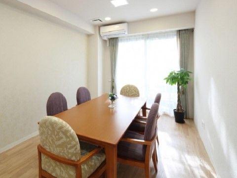 入って突き当たりに窓があり、上部にエアコンを完備した部屋。長テーブルを置いて、６名が席につけるよう配置している。