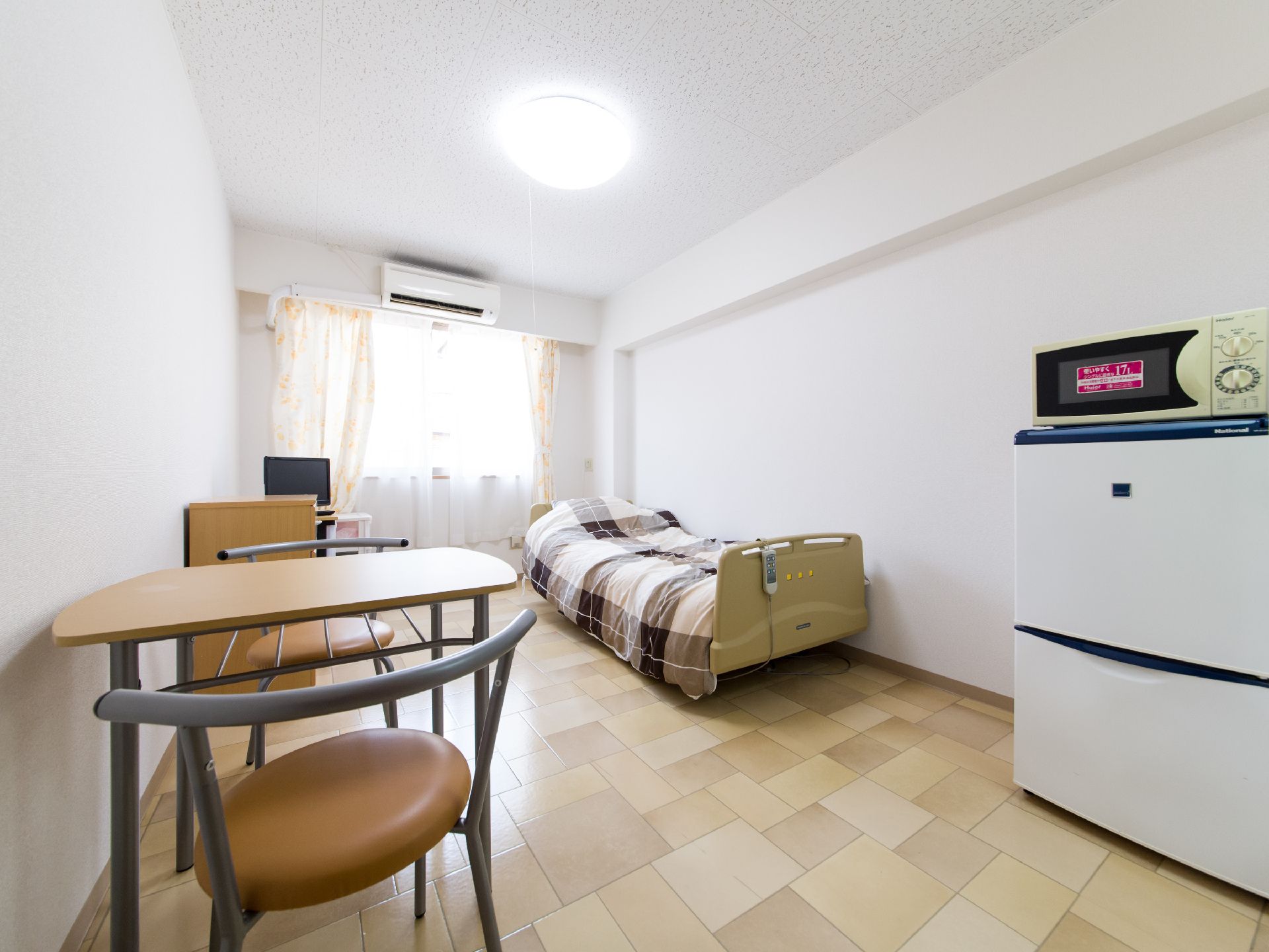 広々とした明るい空間には、介護用ベッドや冷蔵庫、電子レンジ、テーブルセットなど必要最低限のアイテムが揃っている。