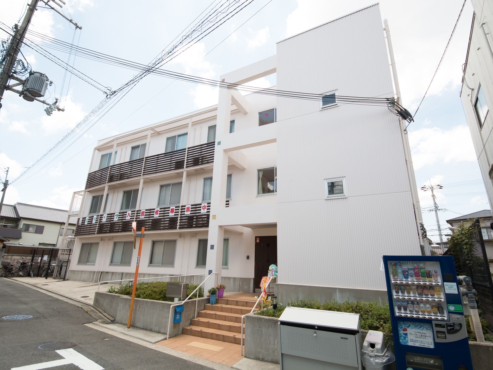 新築のマンションのような外観。壁は白く、おしゃれで清潔感がある。玄関まではスロープもあるので車椅子をご利用の方も安全に出入りできる。