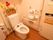 木目調の床、白い壁のトイレである。洋式便座を完備している。壁側にはナースコール、手すりなどが備えつけられている。