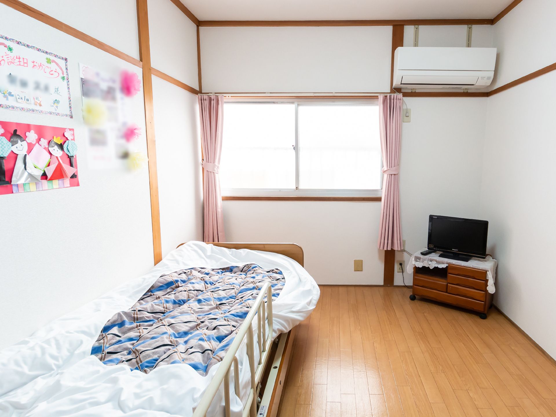 窓から日差しが入り、備え付けの介護ベッドやテレビなどがある居室