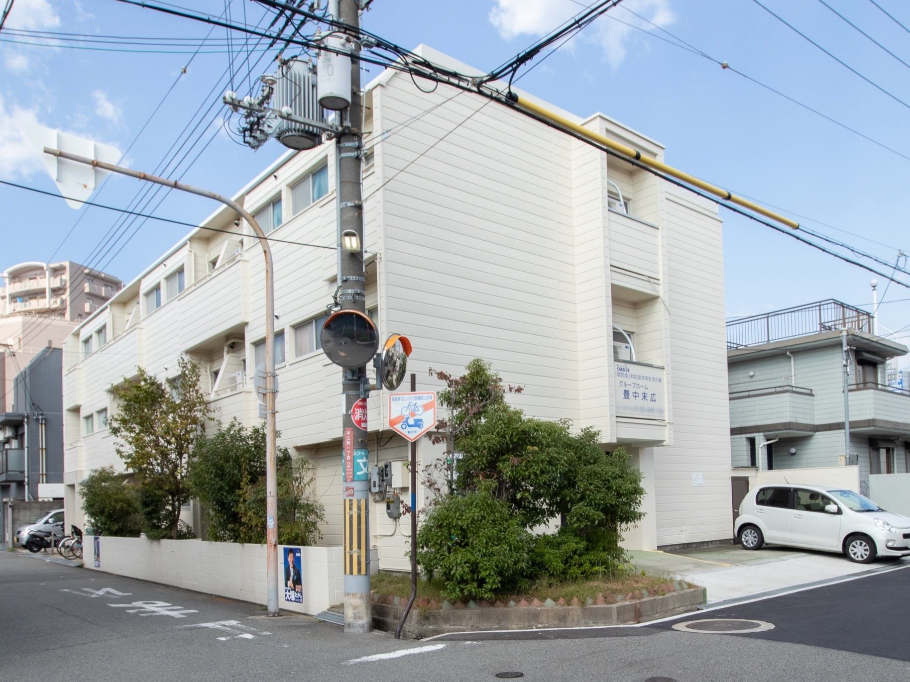 施設はアパートなような外観の３階建ての建物である。建物前には、駐車スペースや庭木が植えられた花壇が設けられている。