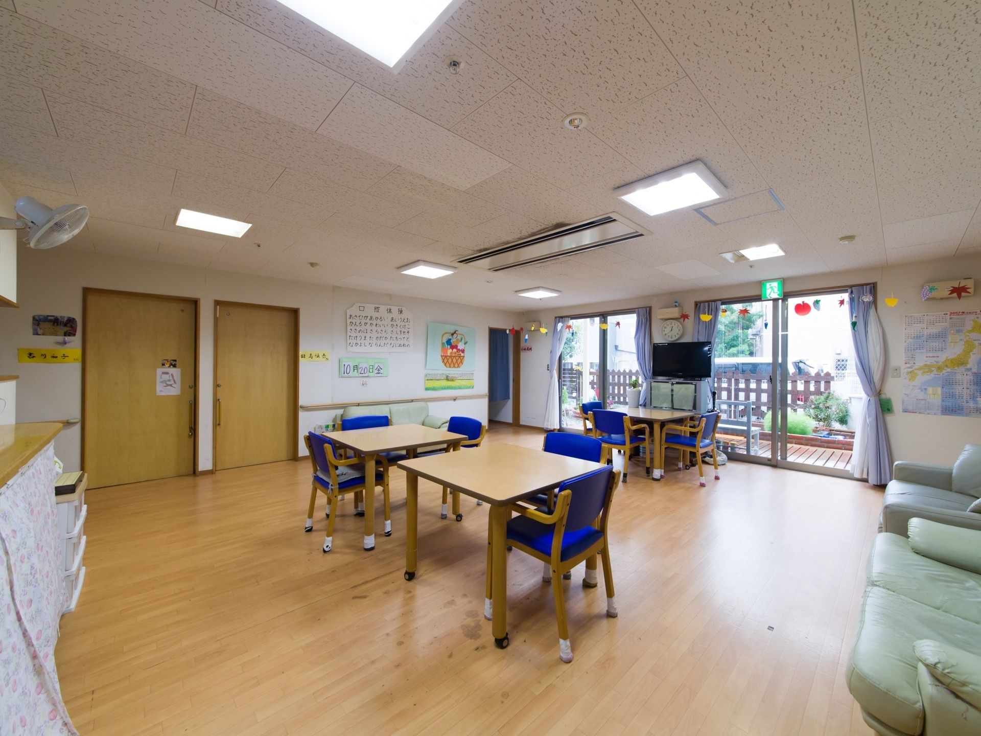 装飾されて華やかなリビング。テーブル同士の間隔は広く取ってあり広々したスペース。窓から光が差して明るい。