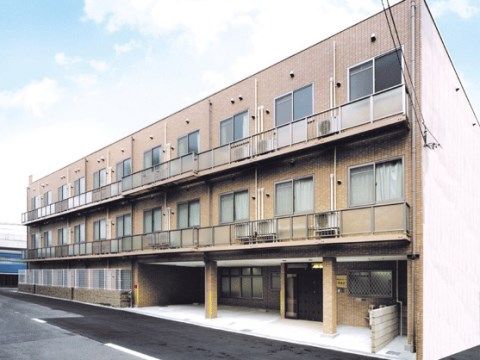 建物入口に庇が付いている、ベランダ付きの三階建ての建物