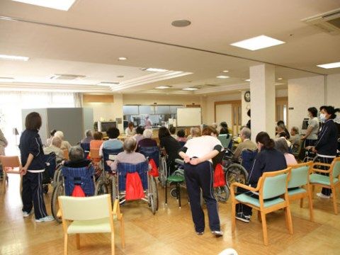 キッチンのある食堂に集まり、車椅子や椅子に座っている入居者たち