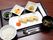 長方形の白いお皿に美しく並べられた卵料理、ニンジン等の野菜、ご飯と汁物、色々なフルーツのデザート等が、トレーに並んでいる。