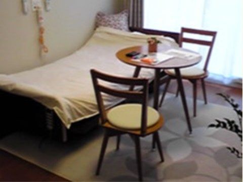 居室にベッドや椅子、テーブルが置かれている。緊急通報装置が設置されているので万が一の際も安心である。