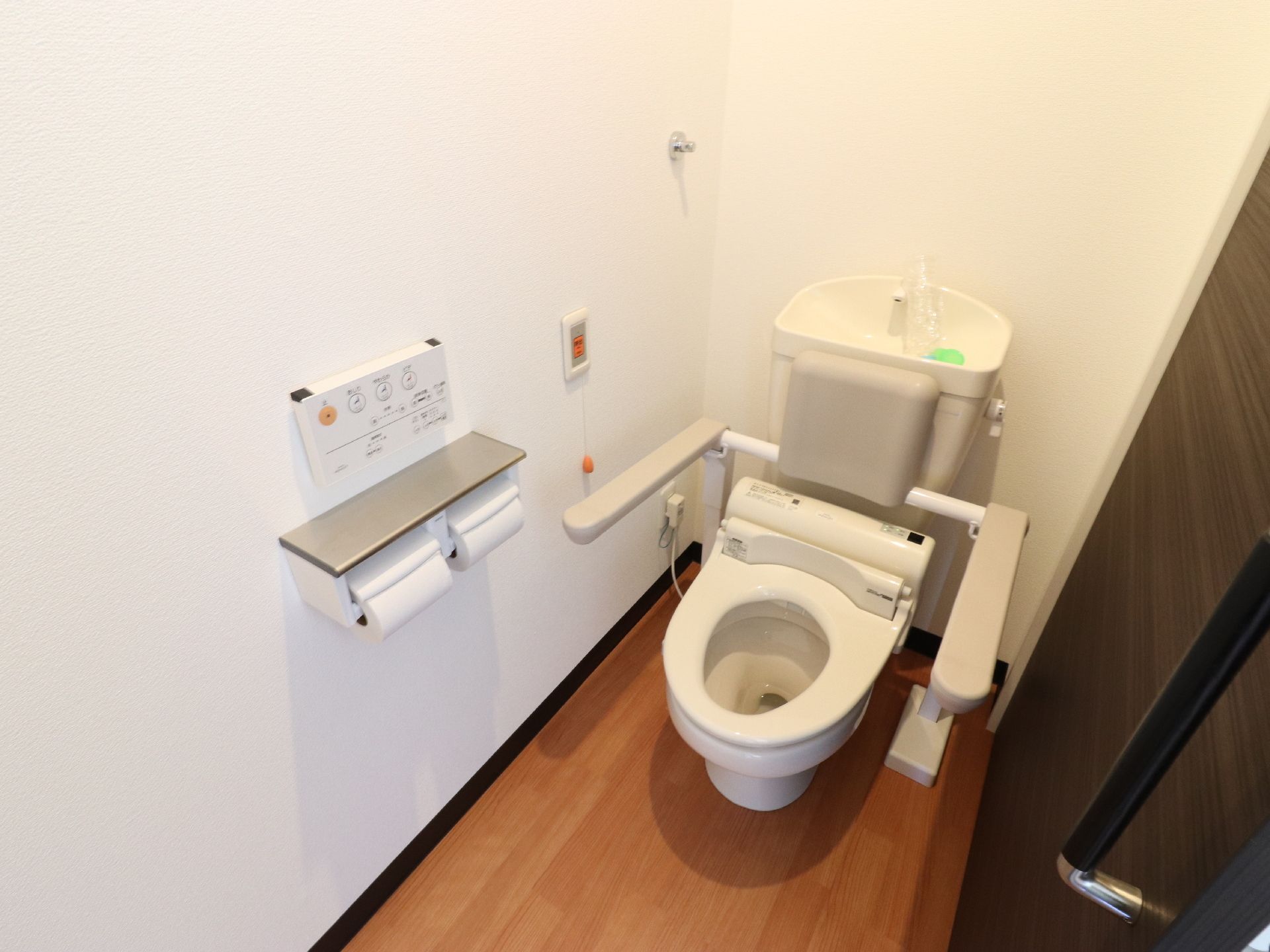トイレには壁には介護スタッフを呼ぶことが出来るボタンがある。便器には手洗い器があり、そこで手を洗うことが出来る