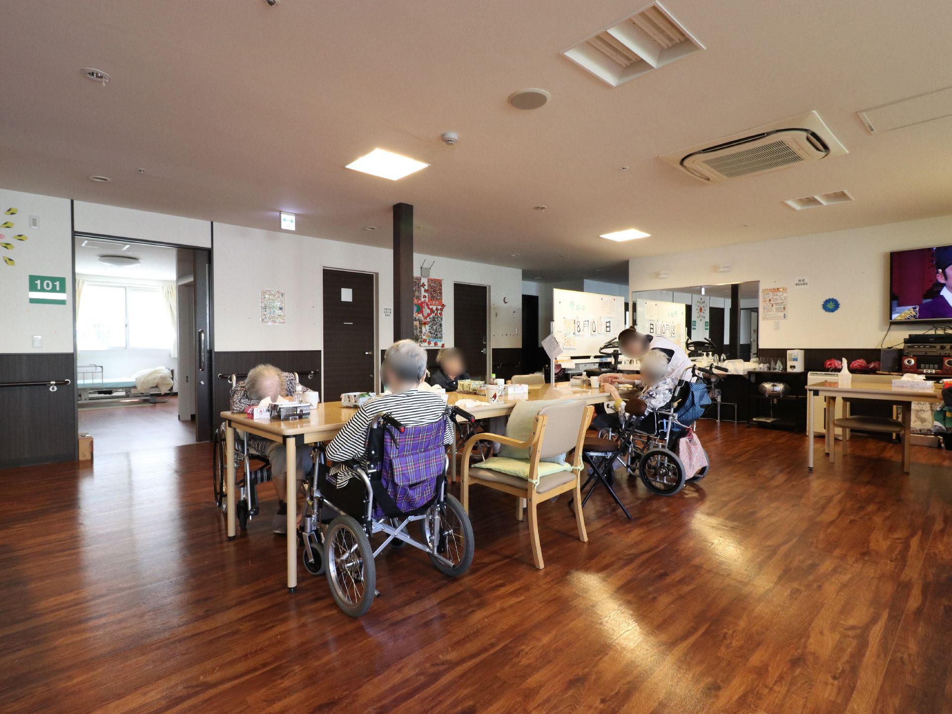 多目的室内にある建具は、木目調の焦げ茶色で落ち着いた雰囲気となっている。右側には行事などで使う白板が設置されている。