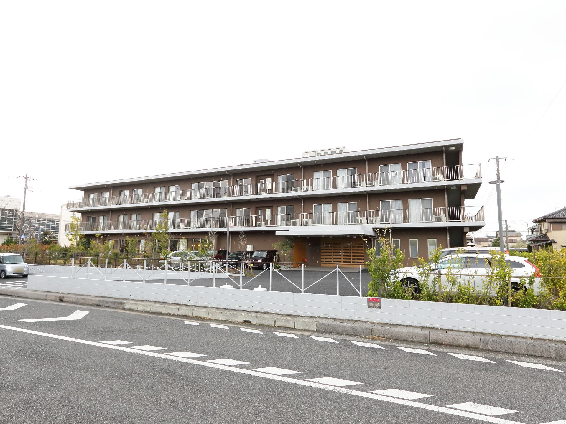 茶色を基調としたモダンテイストな外観。大きな駐車場を完備している。