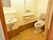 ブラウン系の色でまとめられた落ち着いたデザインのトイレである。引き戸タイプの扉になっている。丈夫な手すりも付いていて安心。