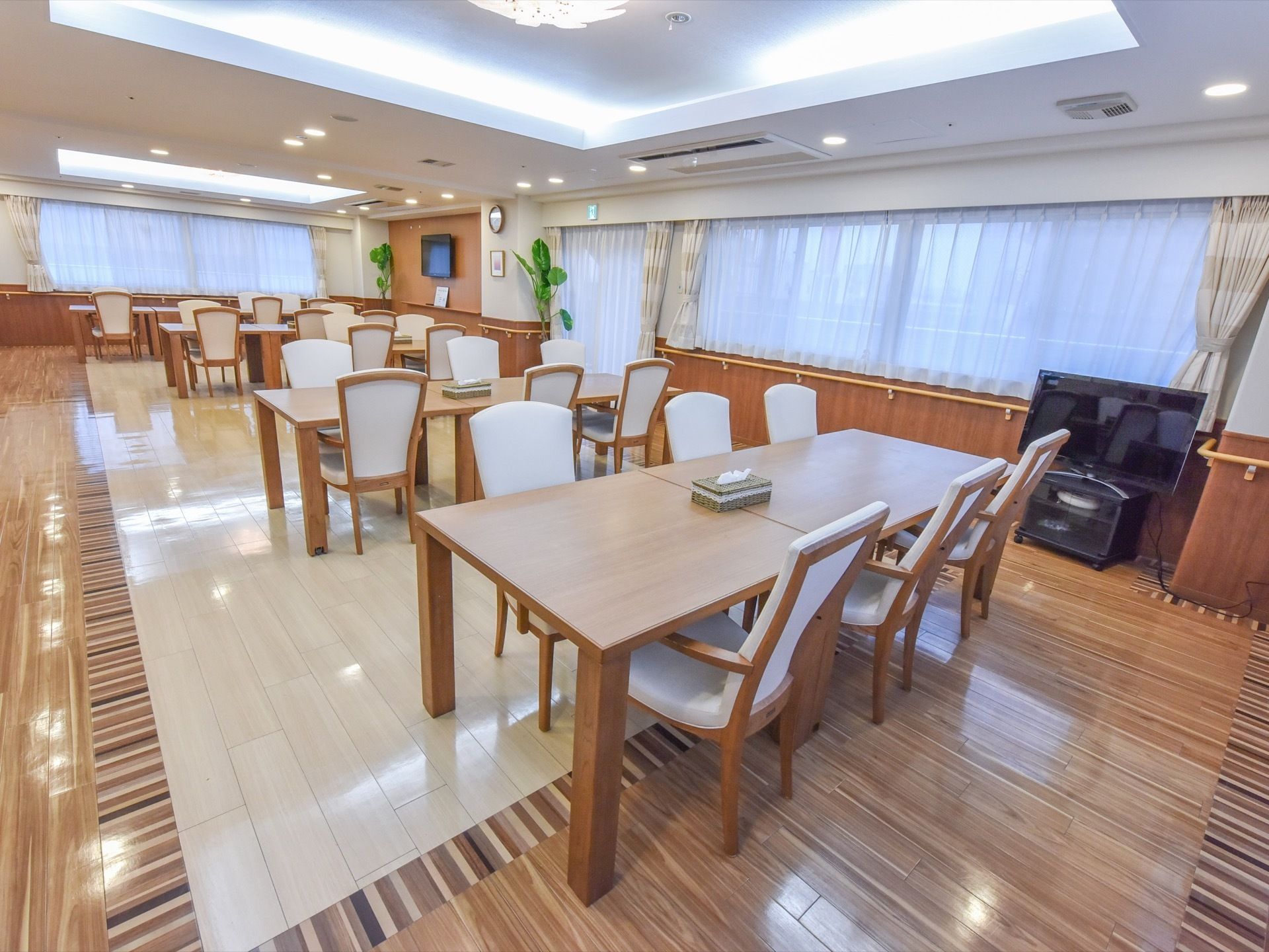 横長の大きな腰高窓があり、自然光が差し込む明るい食堂である。窓のすぐ下の壁には、長い手すりが取り付けられている。