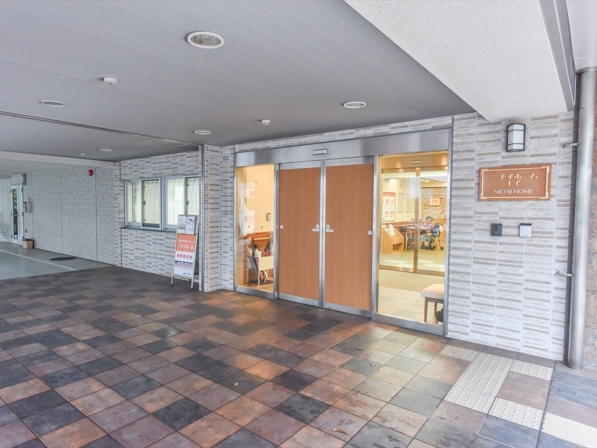 ライトグレーの屋根が、自動ドア前方に設置されている。出入口の前まで車で入れるように、広いスペースが確保されている。
