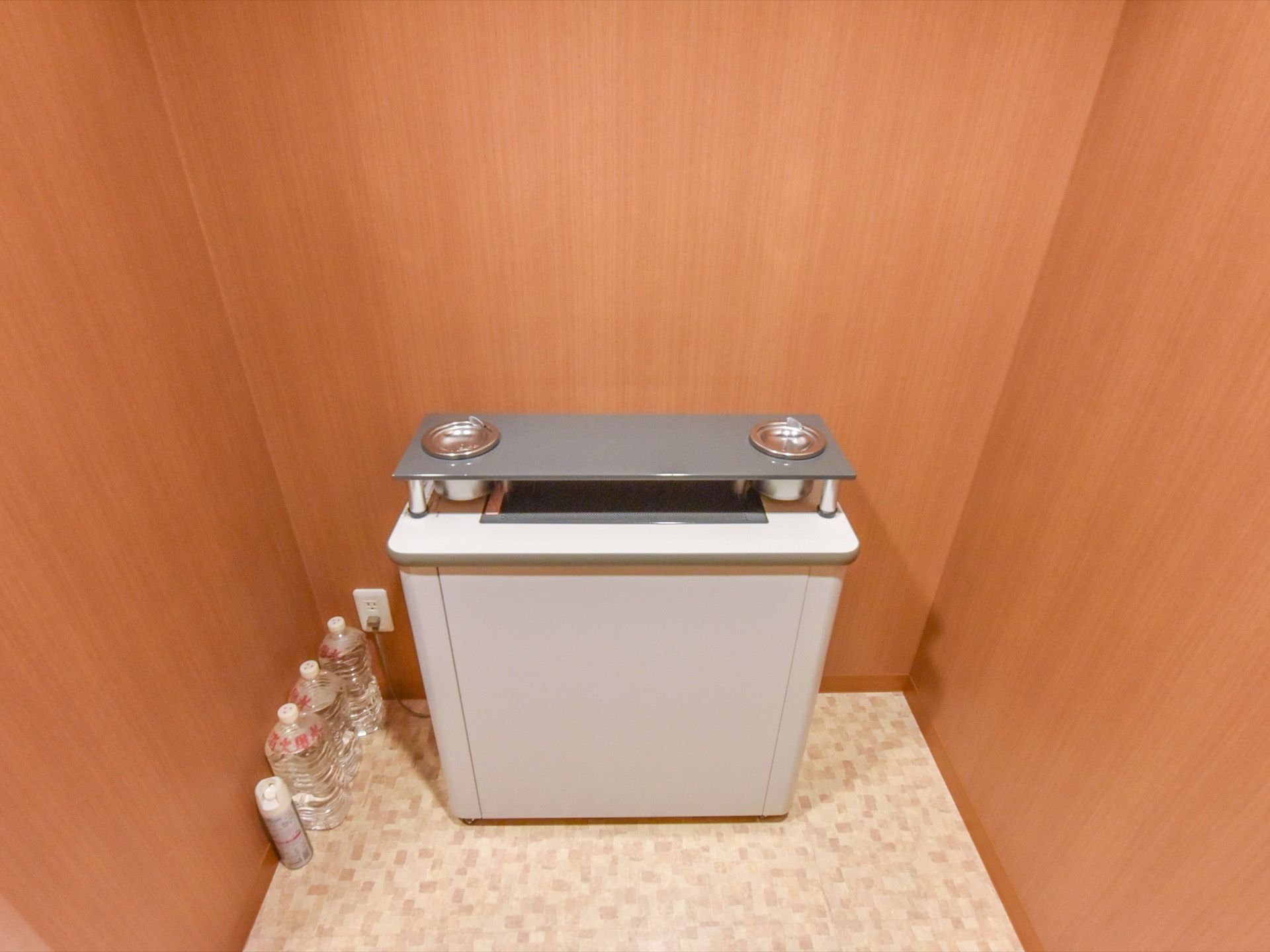 白とグレーが組み合わされたシンプルなデザインの機械の左側に、水が入ったペットボトルが３本並べて置いてある。