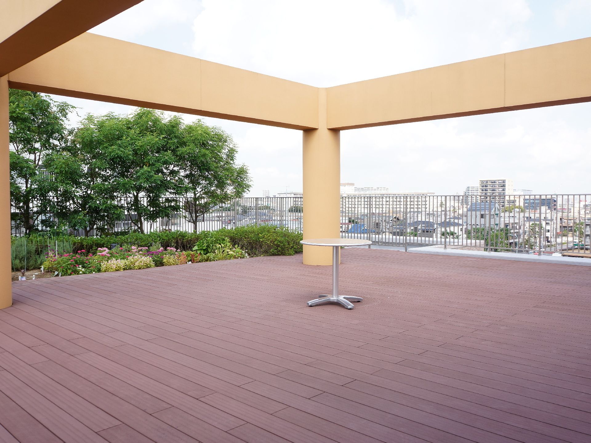 屋上には、広いウッドデッキと綺麗に手入れをされた庭園がある。デッキには柱や丸テーブルが置かれている。