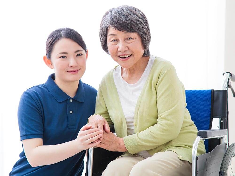 車椅子に座っている高齢女性と付き添いの女性ヘルパー