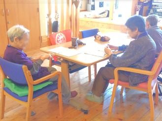 3人の入居者がテーブルを囲み、何かをしている様子。日当たりがよく、気持ちよさそうな空間。
