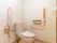 手すりが２カ所に備え付けられた、洋式のトイレである。淡いピンク色を基調とし、あたたかい雰囲気がただよう。