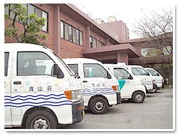 送迎車並ぶ施設前