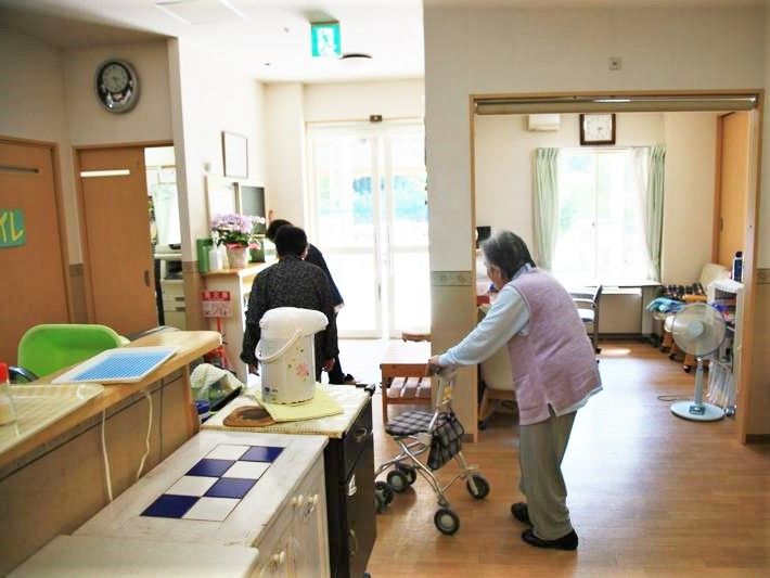 玄関までシルバーカーで移動している入居者。トイレには「トイレ」と書かれた紙が貼られている。