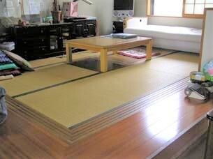 畳敷きの小上がりには掘りごたつがあり、窓際には白いソファも置かれている。座布団が積み上げられているなど、家庭的な雰囲気。