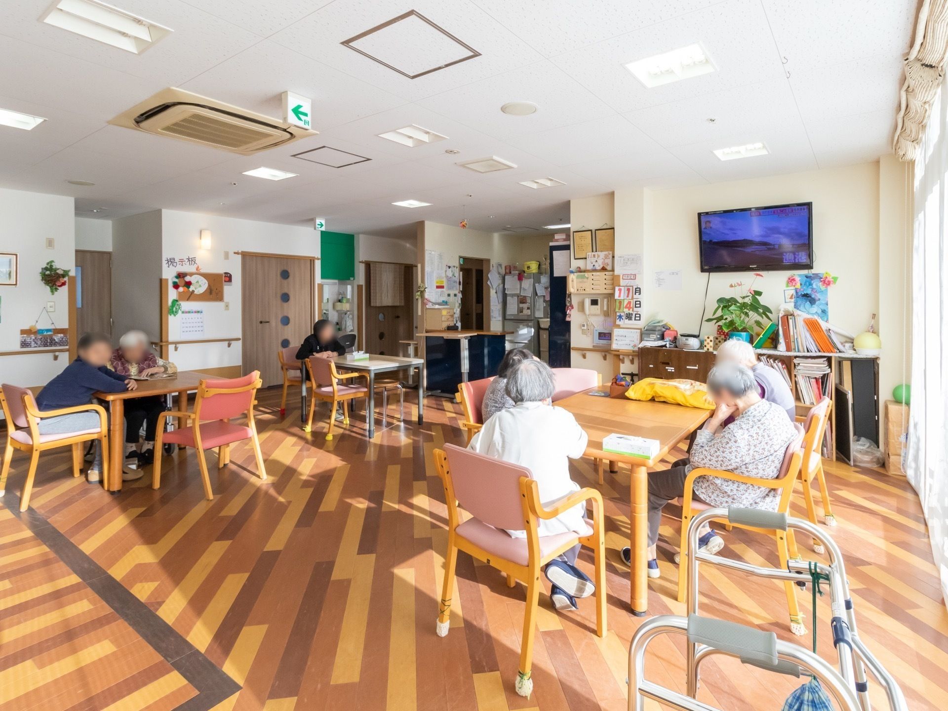 テーブル、椅子、テレビがあるリビングでそれぞれ自由に時間を過ごす入居者
