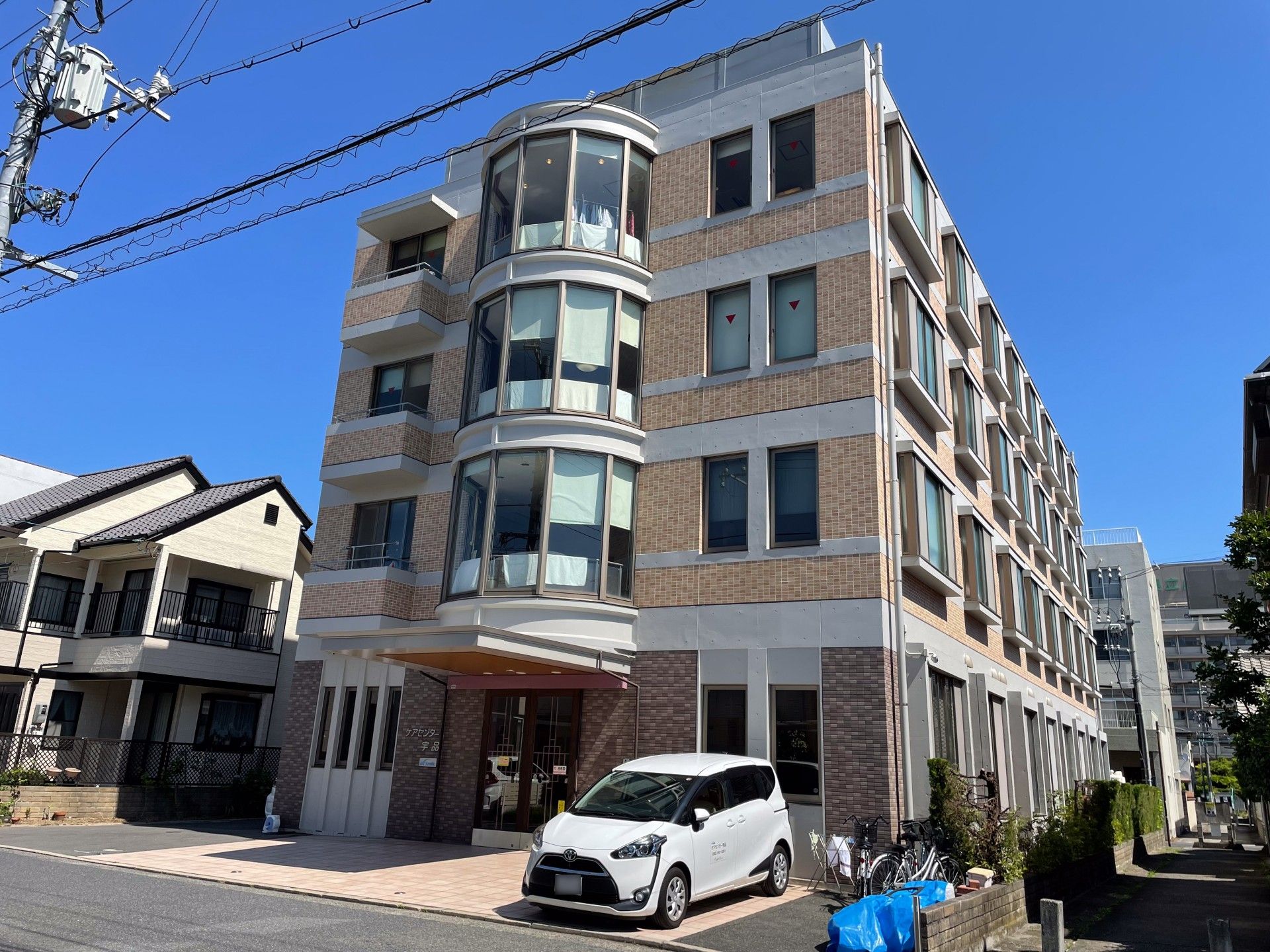 4階建ての建物はレンガ調の外壁で日当たりのいい場所に建っていて、側面にはサンルームのような場所もある。