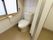 白いタイルの壁に囲まれたトイレがある。大きな窓がついている。ドア部分はカーテンになっており、壁には手すりが設置されている。