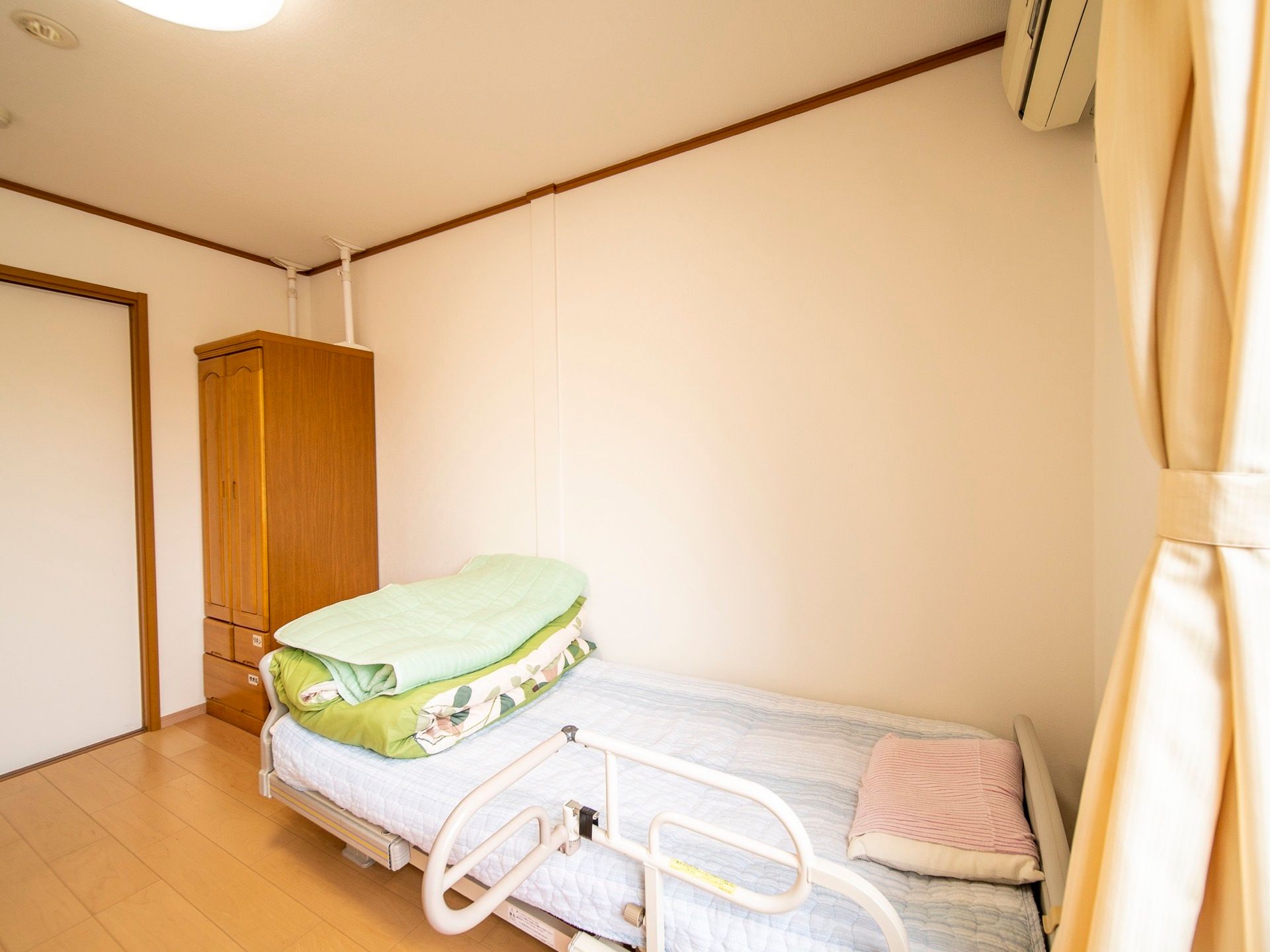 居室には介護用ベッドとタンスが用意されている。窓からは日差しが入り明るく開放的で、ゆったりくつろぐことができる。