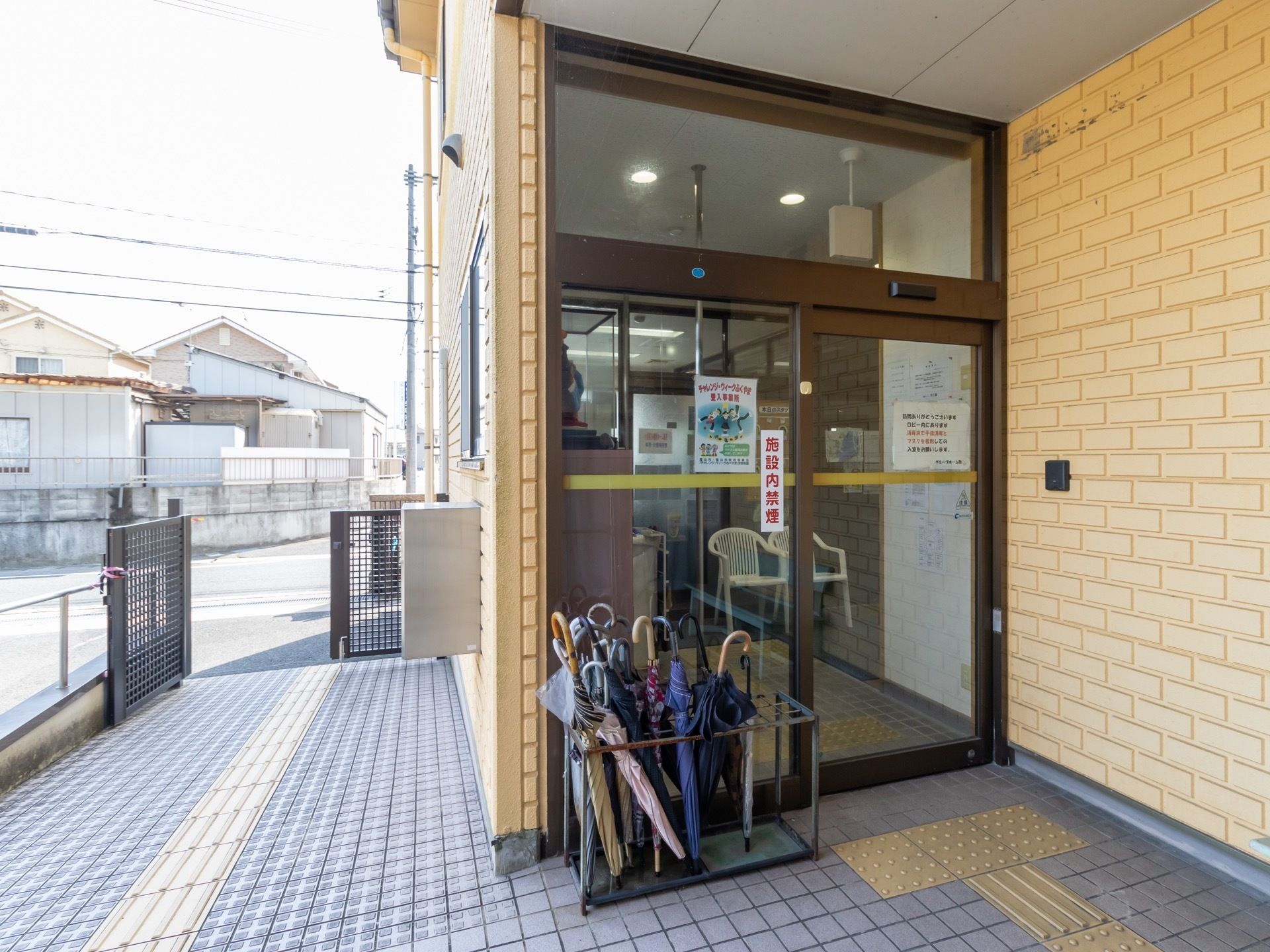 自動ドアが備え付けられている玄関。玄関の前にはスロープがあり、スロープの中央には点字ブロックが設置されている。