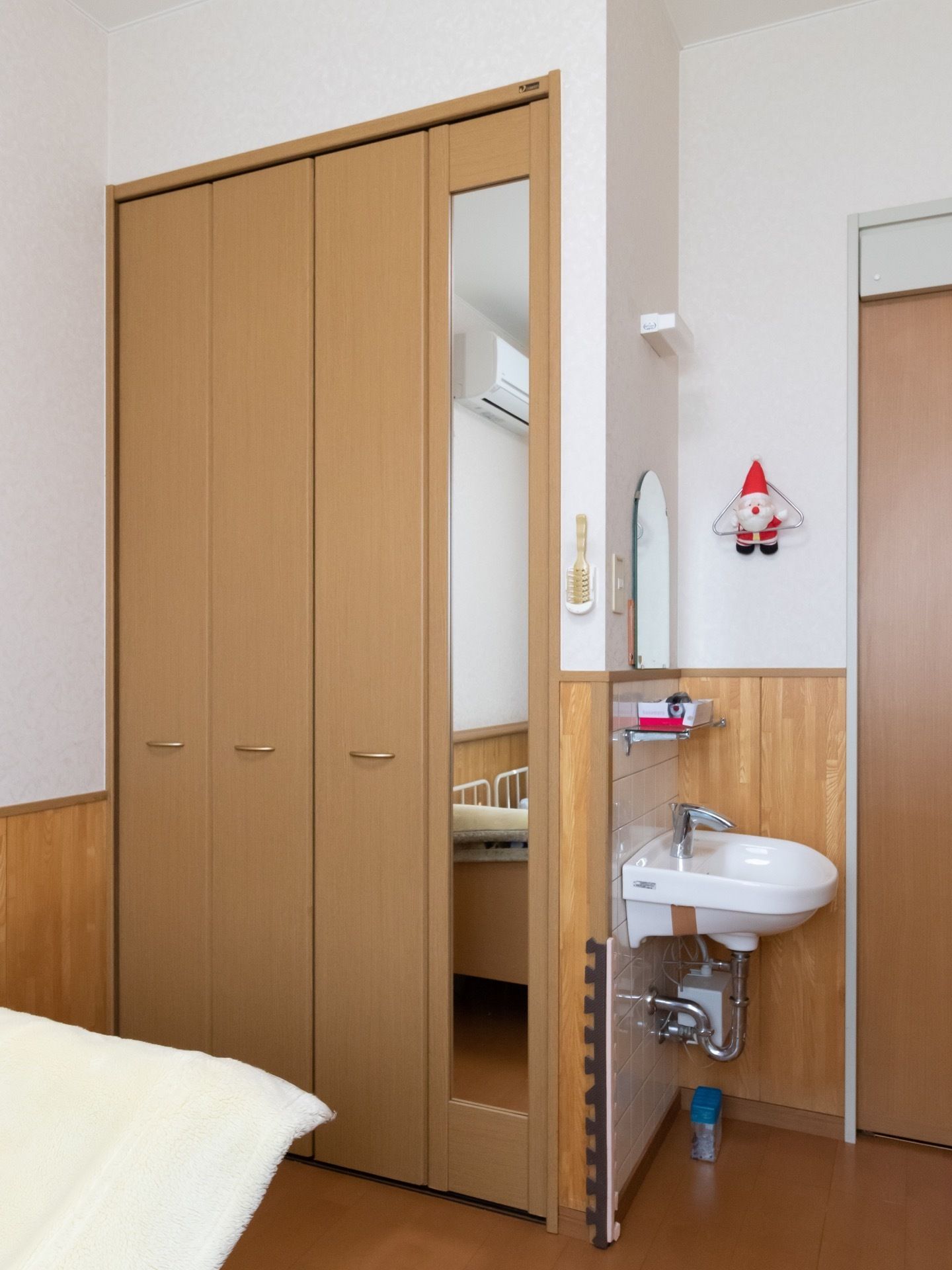居室の壁の一画に、洗面台とクローゼットが完備されている。クローゼットの扉の一部には縦長の鏡も取り付けられている。