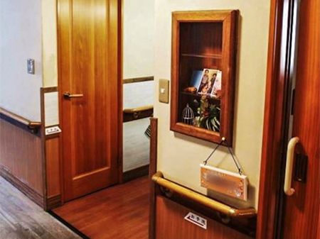 居室の入口には戸棚が設けられており、入居者様の写真や小物が置かれている。入口の扉は、茶色い引戸が取りつけられている。