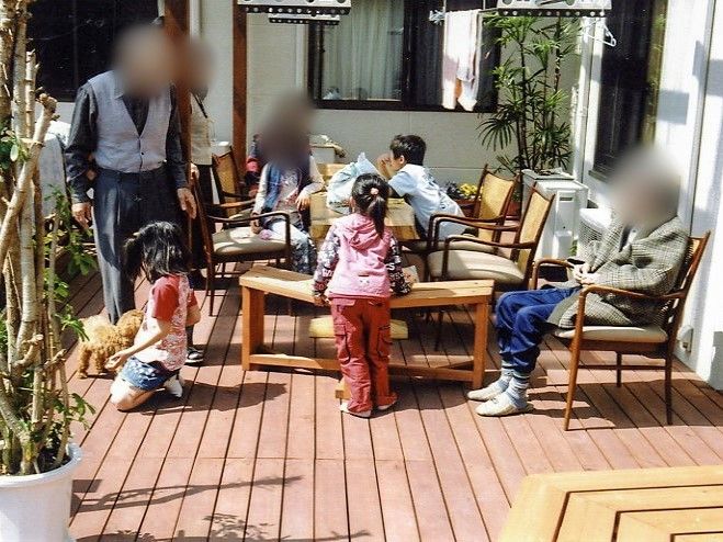 ウッドデッキは広々としたスペースがあり、椅子やテーブルが並べられている。椅子には、入居者様や子どもたちが座っている。